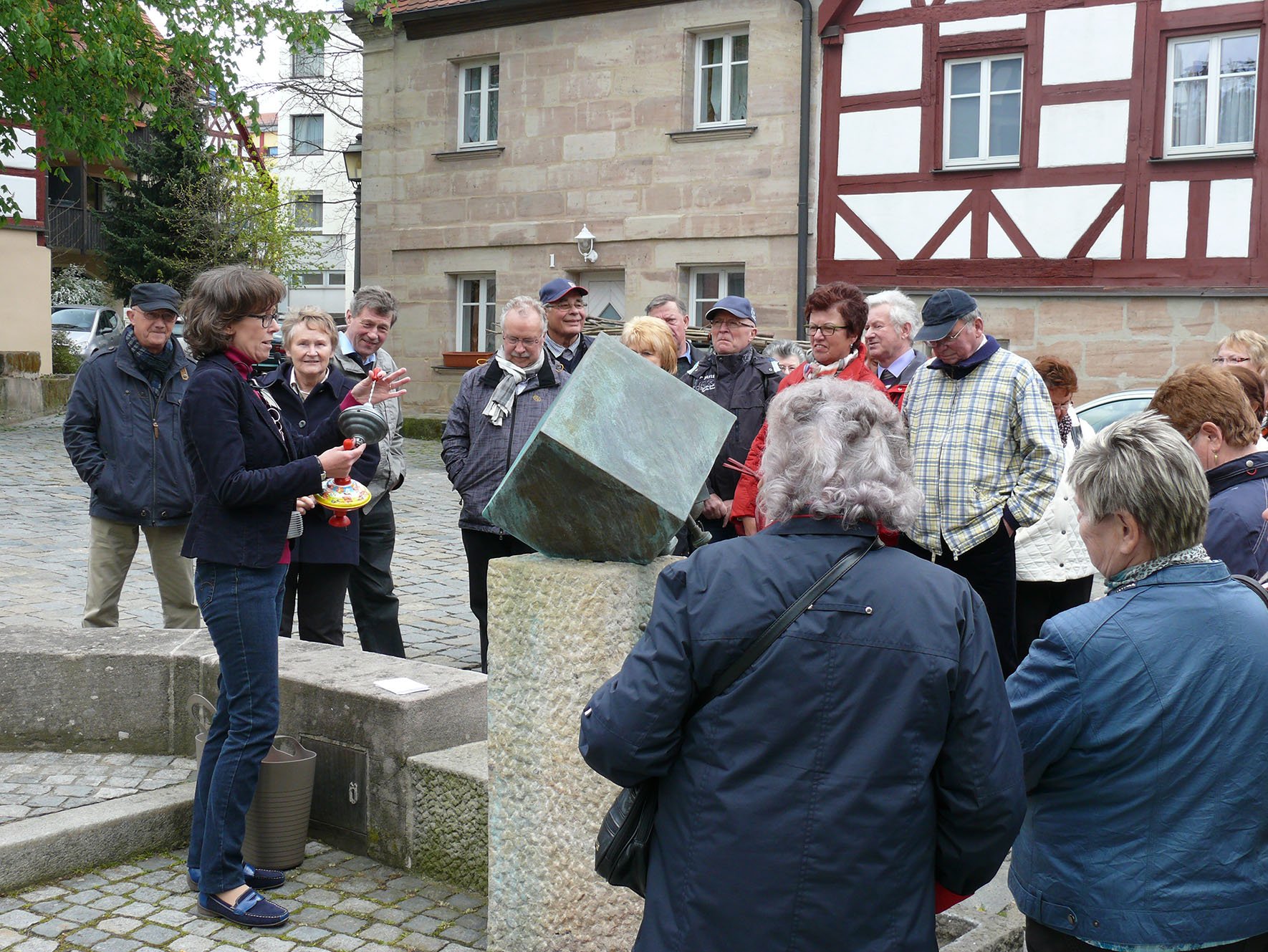 Teilnehmerinnen und Teilnehmer einer Stadtführung beim Spielzeugbrunnen auf dem Koppenplatz in Zirndorf